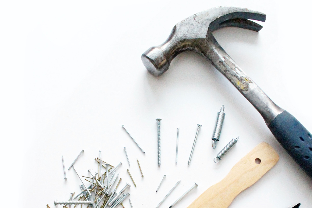 A hammer with some nails, screws, and springs